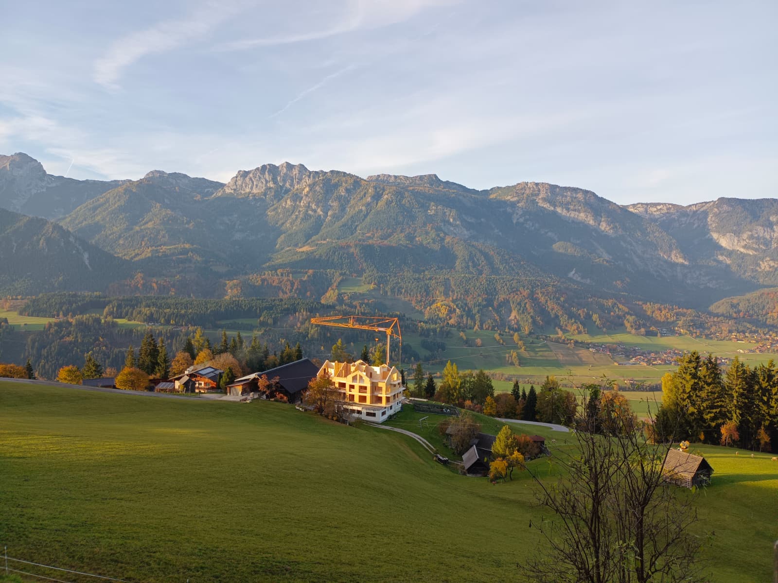 Landschaft mit Häusern im Vordergrund und Bergen im Hintergrund bei Sonnenuntergang